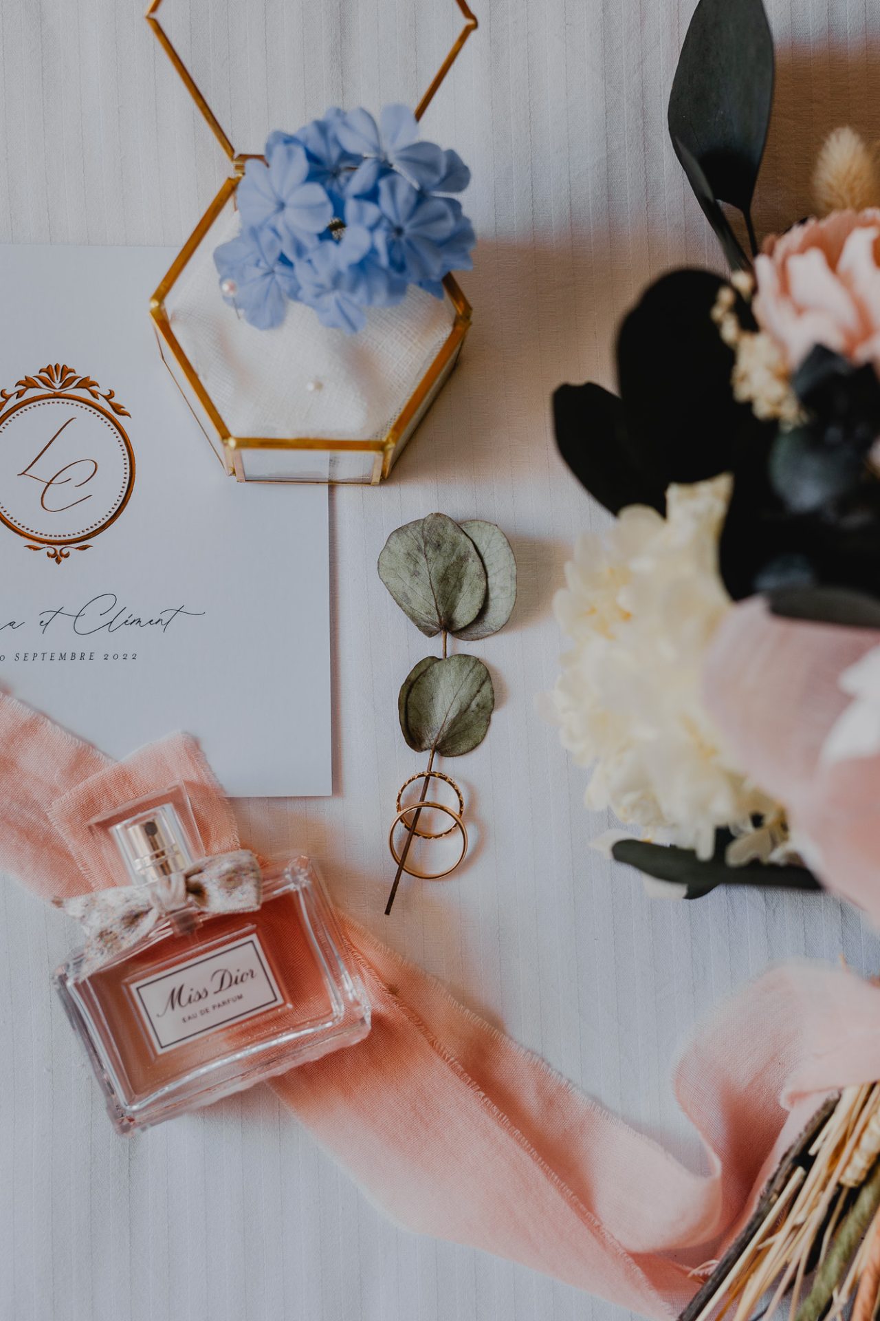 flatlay du parfum, la bague, la papeterie et les fleurs pendant les préparatifs du mariage